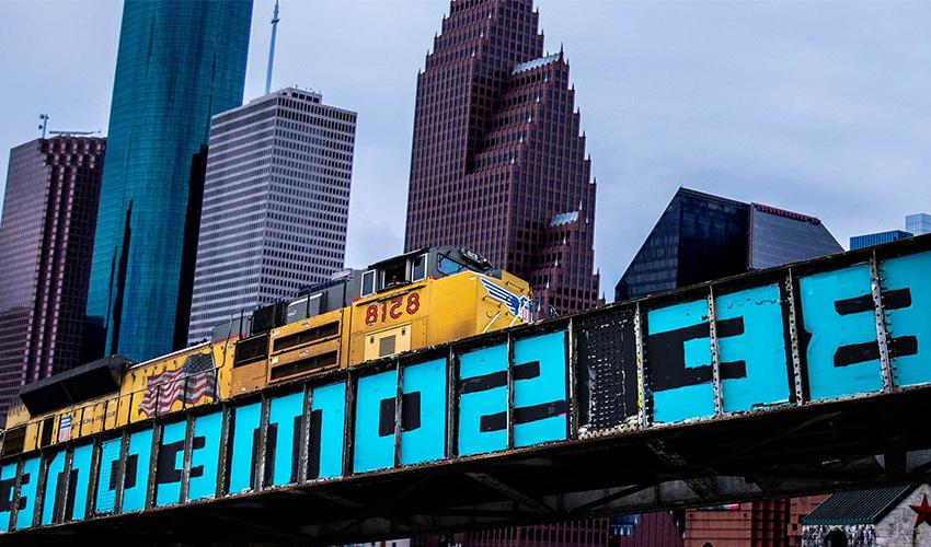 休斯顿的建筑物和火车轨道，画着“Be Someone”。.
