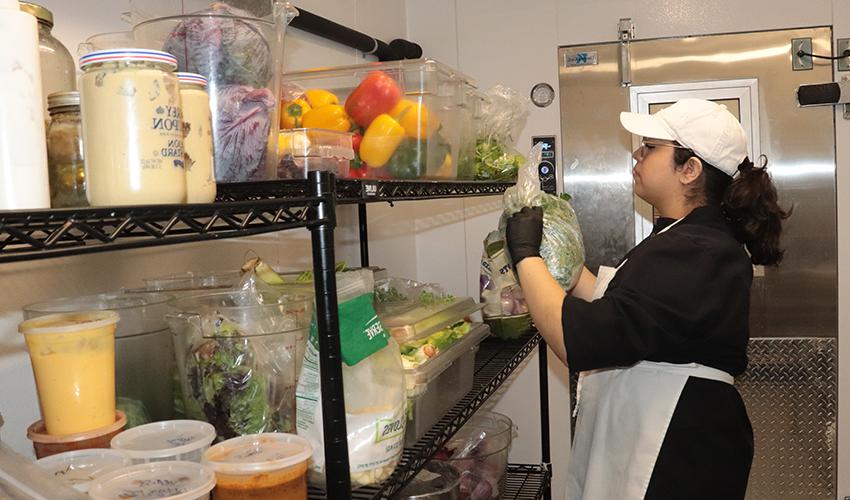 烹饪艺术专业的学生在冰箱里找蔬菜.