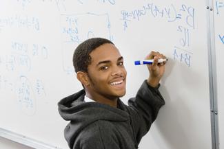 Male student solving math problem on whiteboard